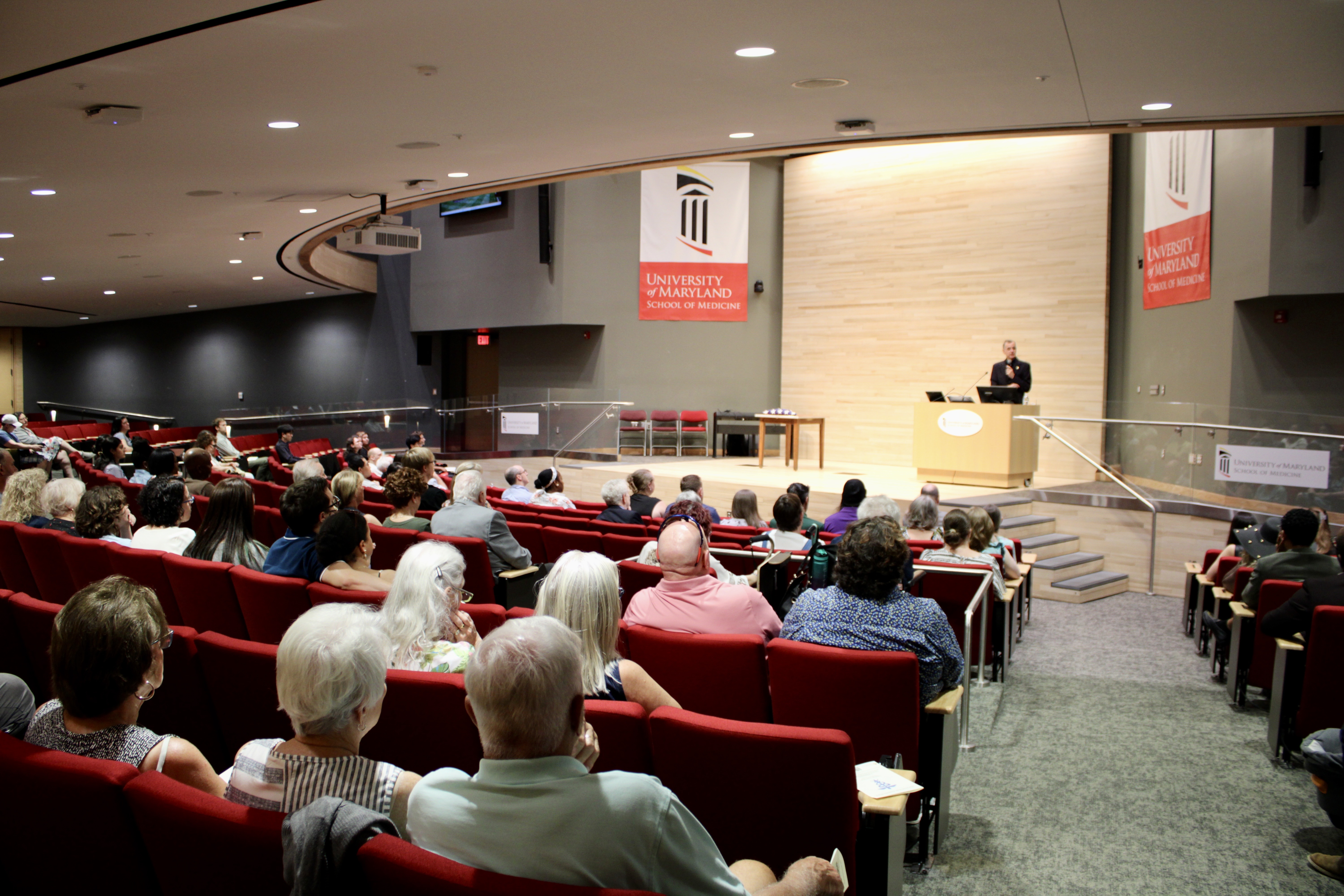 An image taken at the June 2026 Memorial Service showing the crowd and a single presenter