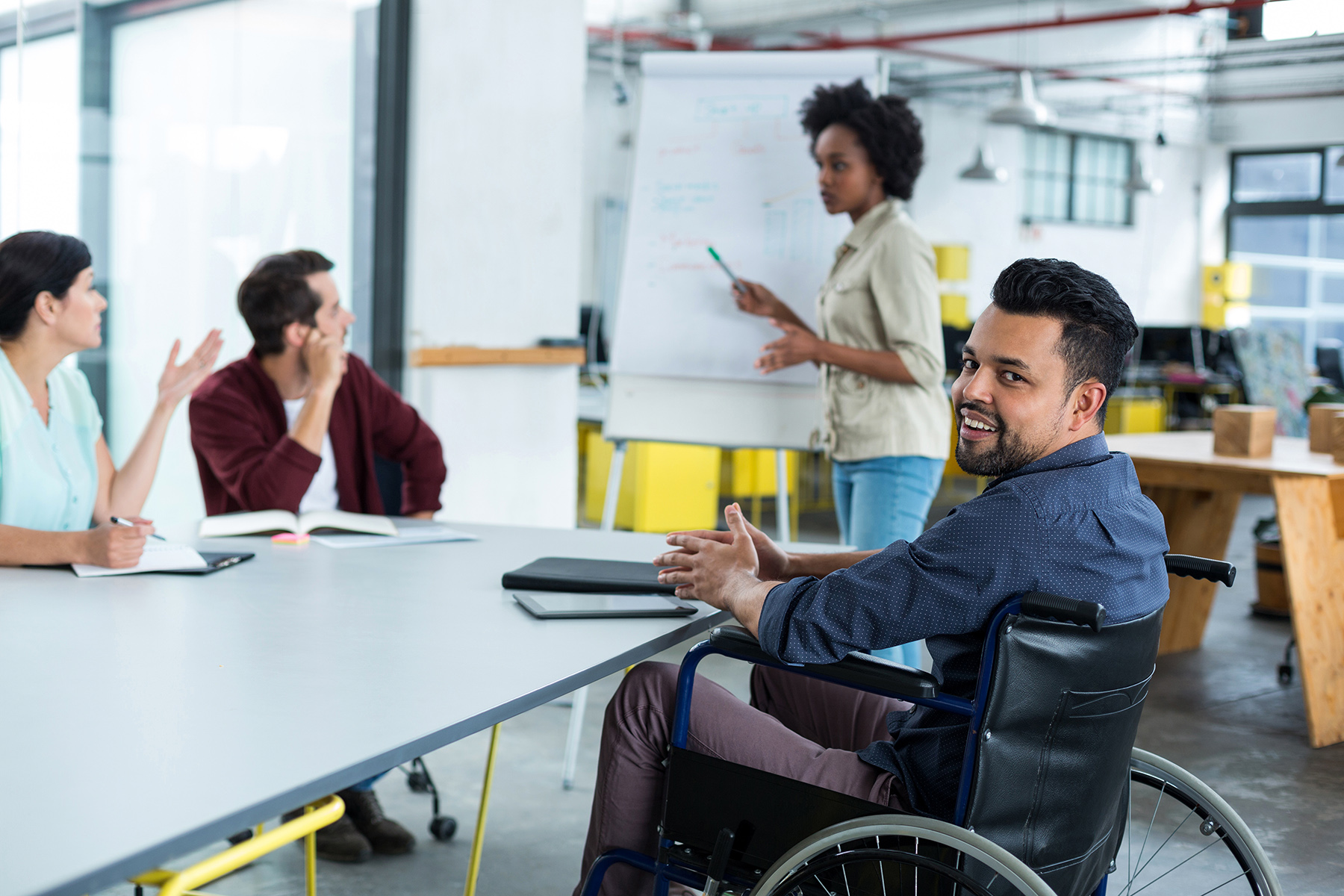A man in a wheelchair is a part of a team in a meeting.