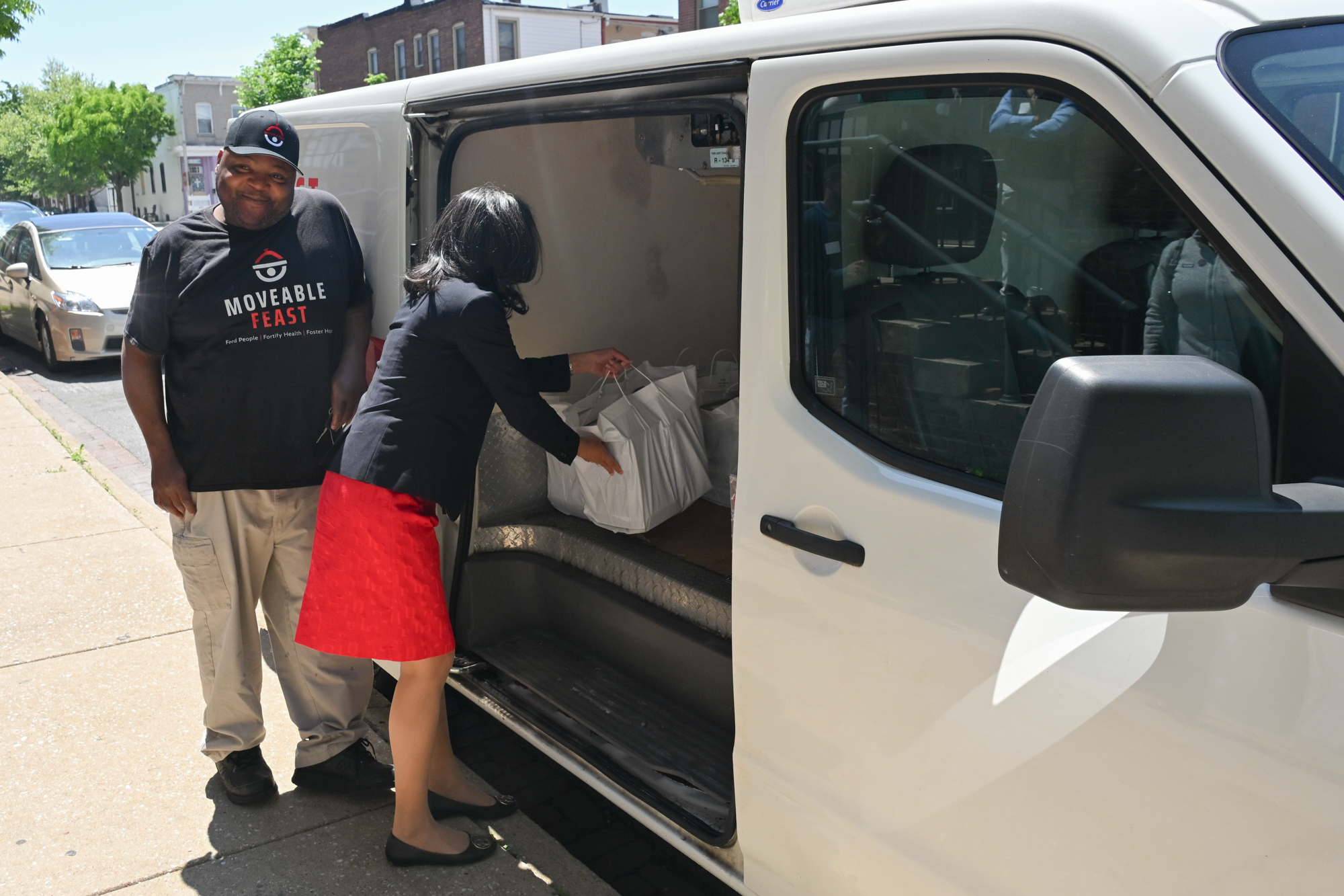 Maryland Health Secretary loads a food delivery fan van with participant meals at the Medically Tailored Meals launch event. 